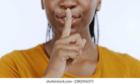 Secret, finger to lips and black woman in studio for privacy, confidential information and face on white background. Mouth zoom, quiet and silence gesture with emoji, gossip or whisper with news