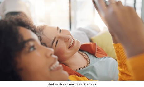 صديقات، فيلم وهاتف على الأريكة، المنزل أو الابتسامة أثناء الدردشة، الضحك الكوميدي أو الاسترخاء معًا على وسائل التواصل الاجتماعي. نساء الجيل زد، والطلاب، والسعادة على أريكة الاسترخاء للاشتراك في البث المباشر، أو التطبيق أو المدونة