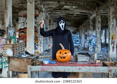 A man with a mask makes a pumpkin