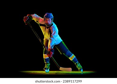 Jonk Meedchen, Hockeyspiller an Uniform an Helm Training, steet mat engem Stéck géint schwaarze Studiohannergrond am Neonliicht. Konzept vu professionnelle Sport, Konkurrenz, Spill, Aktioun, Hobby
