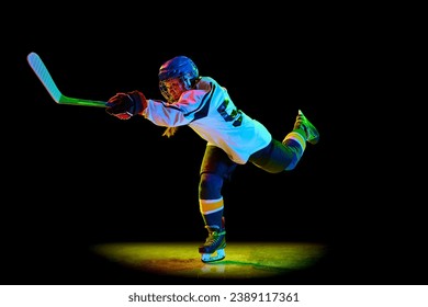 Kompetitivt jonkt Meedchen, Hockeyspiller a Bewegung wärend dem Spill, spillt géint schwaarze Studiohannergrond am Neonliicht. Champion. Konzept vu professionnelle Sport, Konkurrenz, Spill, Aktioun, Hobby