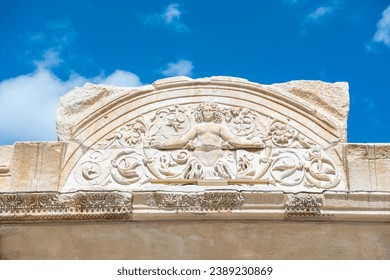 Relevo da Medusa, entre folhas de acanto e pergaminhos, decorando o tímpano acima da porta da cela do Templo de Adriano em ruínas, no antigo sítio arqueológico de Éfeso, na Turquia.