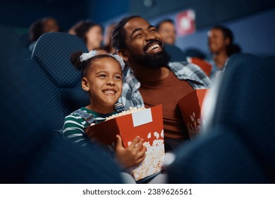 Glécklech afroamerikanesch Papp an Duechter genéissen an der Filmprojektioun am Theater.