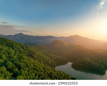 Krásná krajina zelených hor a jezera ráno s východem slunce. Přírodní krajina. Povodí les. Koncept udržitelnosti vody a lesa. Letecký pohled na horu se zelenými stromy.