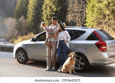 Orang tua, putri mereka, dan anjing di dekat mobil di luar ruangan. Keluarga bepergian dengan hewan peliharaan