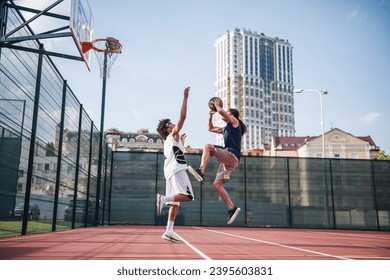 Pemain basket tampan sedang bermain di lapangan basket luar ruangan