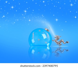 Kartolina e Krishtlindjeve dhe Vitit të Ri me një top transparent, flokë dëbore dhe një figurë dragoi. Sfondi blu i Vitit të Ri me hapësirë ​​reflektimi dhe kopjimi.