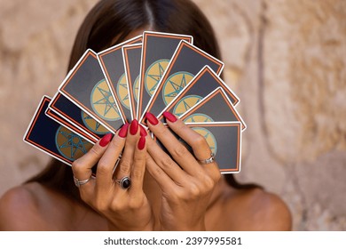 Un fan al cărților de Tarot cu cămăși identice acoperă fața unei fete cu părul închis la modă în timpul ghicirii. Cărți de tarot în mâinile unui ghicitor Palma de Mallorca, Spania