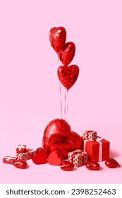 Heart shaped air balloons and gift boxes on pink background
