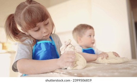 Kinder backen. Sie kneten Teig und Mehl in der Küche. Glückliches Familienleben. Babys backen Pizzateig. Bruder und Schwester backen Kekse. Gemeinsames Kneten von Teig und Mehl.