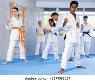 Grupp vu Karate Kanner déi Karate Technik am Fitnessstudio üben..
