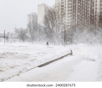 Die einsame Silhouette eines Mannes, der an einem Wintertag durch einen Schneesturm eine Stadtstraße entlang läuft. Schneefall, Schneesturm und Wind im Dezember in Moskau.