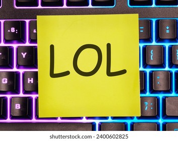 LOL. escrito en una pegatina amarilla en un teclado de ordenador portátil con luz de fondo