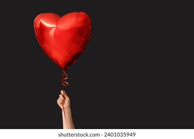 Femeie cu balon cu aer în formă de inimă pe fundal negru. Sărbătoarea de Ziua Îndrăgostiților