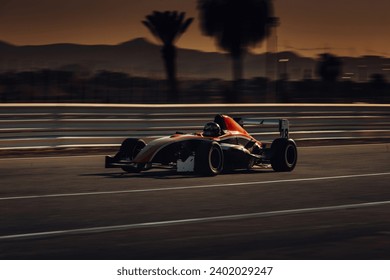 Auto Formuly 1 ide rýchlo na pretekárskej dráhe pri západe slnka