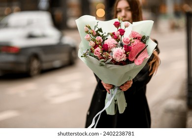 Großer, schöner Strauß rosa und weißer Rosen im Vordergrund, schöne Brünette Frau im unscharfen Hintergrund