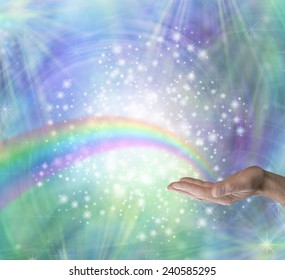 Sending Rainbow Healing Energy - Male hand outstretched with palm up and a rainbow appearing to emerge from his palm surrounded by glittering stars and a blue and green colored background