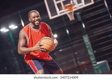 Pemain basket tampan sedang bermain basket di luar ruangan di malam hari