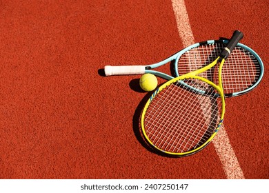 Bola dan raket tergeletak di lapangan tenis profesional berwarna coklat tanah liat. Tampilan dekat bola tenis dan raket di atas sampah di lapangan tenis di taman bermain. Konsep olahraga. Perspektif dari atas