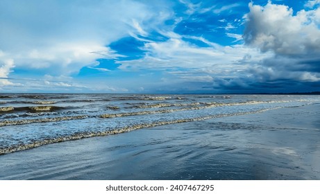 말레이시아 쿠안탄 파항(Kuantan Pahang)의 판타이 아낙 에어(Pantai Anak Air)에 있는 아름다운 해변 일몰의 풍경입니다. 다채로운 하늘과 물결치는 바다 위에 극적인 구름이 있는 모래 해변