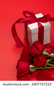 Valentines day card with gift box and rose flowers. On red background with space for your greetings