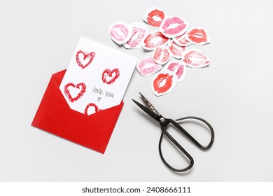 Envelope, card with text LOVE YOU, lipstick kiss marks and scissors on grey background. Valentine's Day celebration