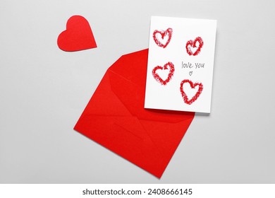 Red envelope and card with text LOVE YOU on grey background. Valentine's Day celebration