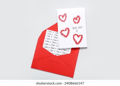 Red envelope and card with text LOVE YOU on grey background. Valentine's Day celebration