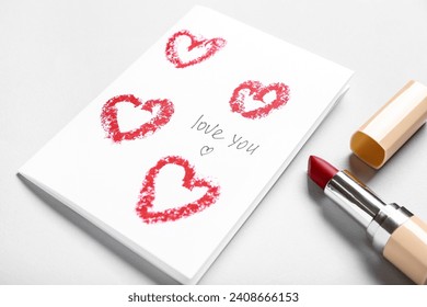 Greeting card with text LOVE YOU and red lipstick on grey background, closeup. Valentine's Day celebration