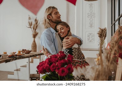 Young romantic couple embracing while celebrating anniversary at the decorated home