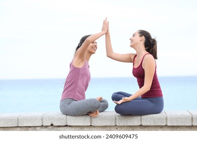 Doi yoghini dau cinci făcând yoga pe plajă