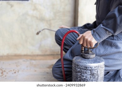 Disinfestatore professionista in tenuta da lavoro che spruzza pesticidi o insetticidi con un serbatoio spruzzatore.