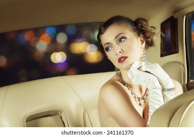 Junge und schöne prominente Frau, die in einem Luxusauto sitzt