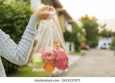 Woman hands carry in a plastic bag fruits on the way home. Hands holding plastic bags for shopping. Set zero waste plastic free concept. Sustainable lifestyle concept.
