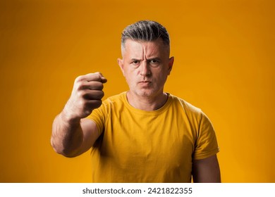 Portrait vum Mann rosen a rosen, déi Fauscht frustréiert a rosen ophëlt wärend hie mat Roserei iwwer gielem Hannergrond jäizt. Aggressivt Konzept.