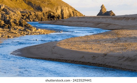 Përrua nga pellgjet e Bosherston Lily duke gjarpëruar nëpër rërën e plazhit të Broad-haven South , me shkëmbin e kishës në distancë