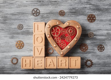 Rustik bir görünüme sahip bronz renkte boyanmış, dişli çarklarla süslü steampunk tarzı bir kalp. Yakınına "LOVE HEART" yazan ahşap bloklar yerleştirilmiş. Sevgililer Günü için kavramsal bir tebrik kartı.