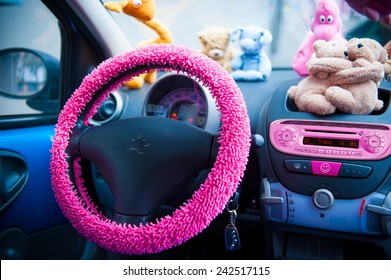 Autoinnenraum mit rosafarbenen Details und Stofftieren auf dem Armaturenbrett.