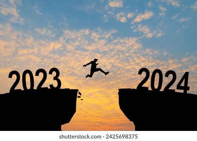 Burri duke kërcyer në shkëmb 2024 mbi greminë me gurë në perëndimin e mrekullueshëm të diellit. Koncepti i Vitit të Ri. 2023 bie në humnerë. Mirësevini 2024. Njerëzit hyjnë në vitin 2024, ide kreative.