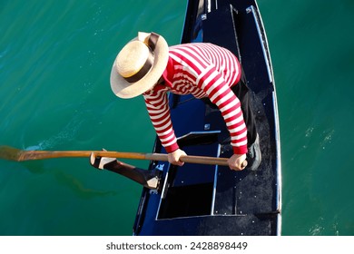 Venetian gondolier with hat rowing on gondola on grand canal in Venice in Italy in Europe