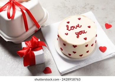 Bento cake with text Love You, takeaway packaging and gift box on grey table. St. Valentine's day surprise
