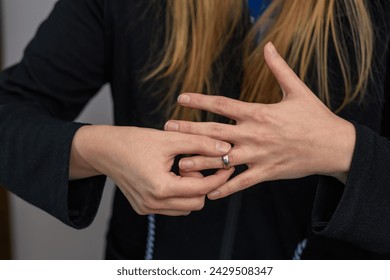 A woman takes off a silver wedding ring from her finger, separation and divorce
