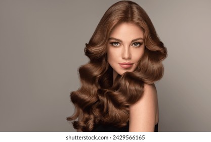 Gadis model berambut cokelat yang cantik dan tertawa dengan rambut ikal panjang. Gaya rambut wanita yang tersenyum dengan ikal bergelombang. Manikur kuku merah. Potret mode, kecantikan, dan tata rias
