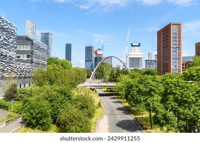 Pont moderne au-dessus d'une rue menant au centre-ville de Manchester par une journée ensoleillée de printemps. Des gratte-ciels modernes sont en arrière-plan.
