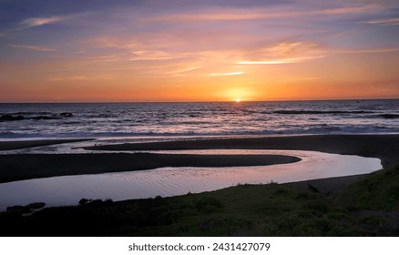 Coucher de soleil sur la pittoresque côte centrale de Californie. L'eau qui s'écoule dans l'océan provient des ruisseaux intérieurs débordant à cause des fortes pluies hivernales