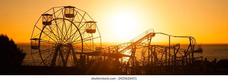 Silueta de la noria gigante en Adventure Island Fun Park recortada contra el sol poniente al atardecer