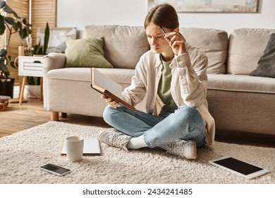 adolescente inteligente lendo livro enquanto faz lição de casa entre dispositivos e xícara de chá, geração z