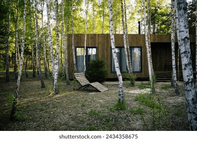 Small wooden modern house with big windows in the birch forest
