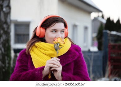 happy girl in bright clothes and headphones with rose flower