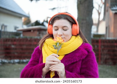 happy girl in bright clothes and headphones with rose flower